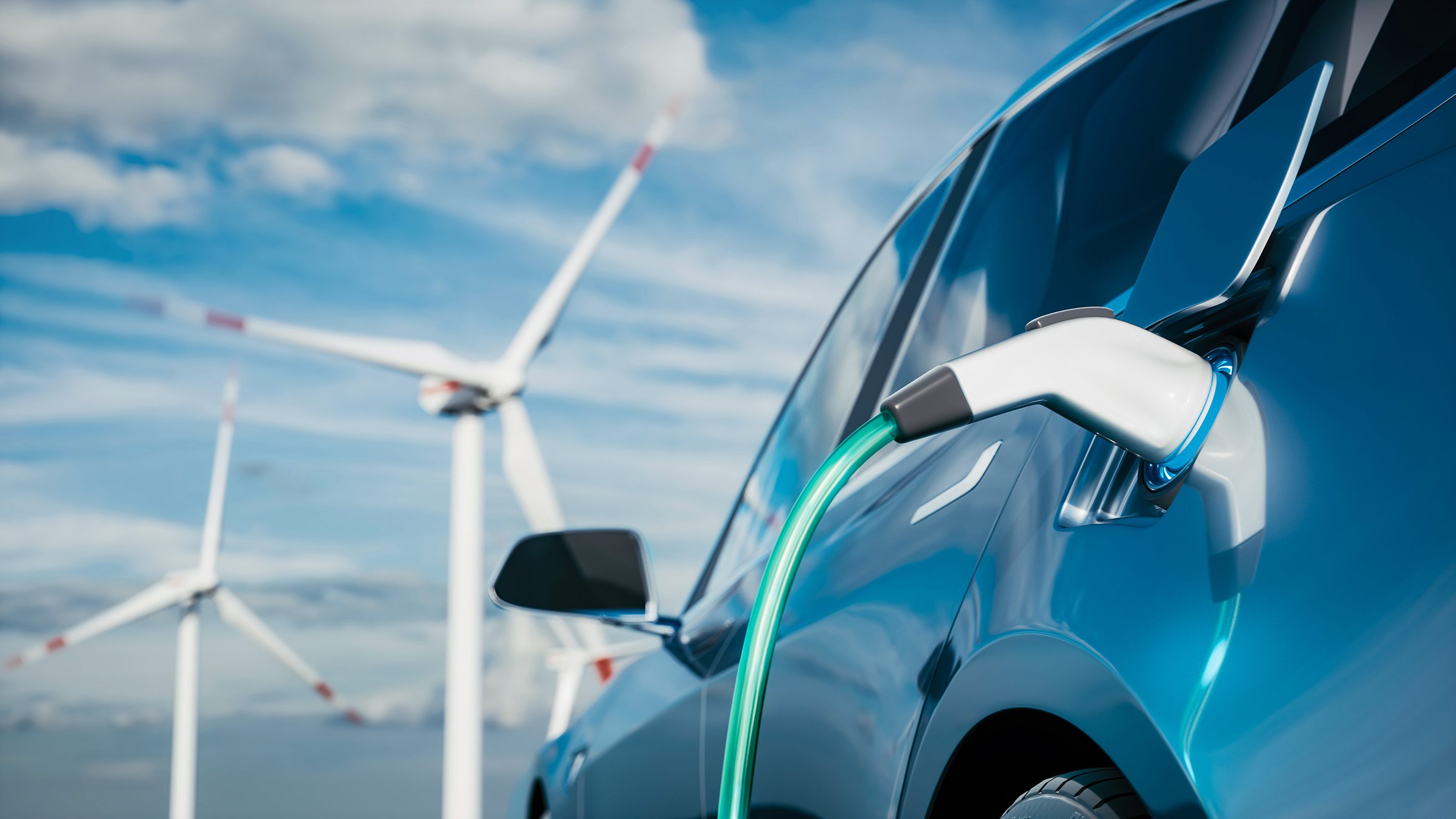 Electric vehicle charging with wind turbines in the background
