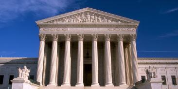 Supreme Court building, with majestic columns, under a blue sky.